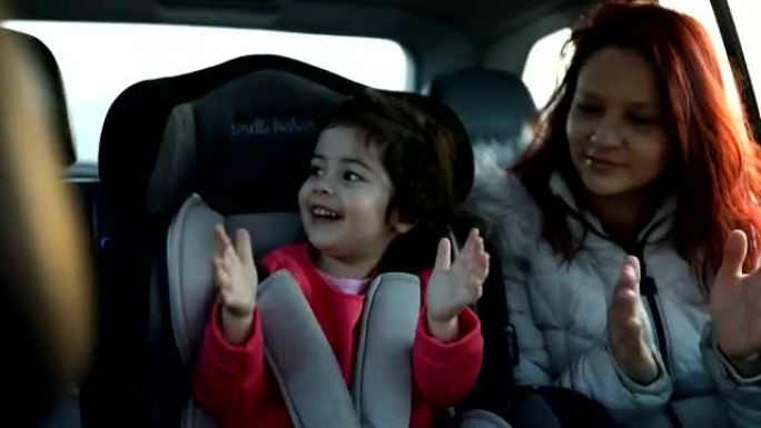 母亲和小女儿坐在汽车后座上
