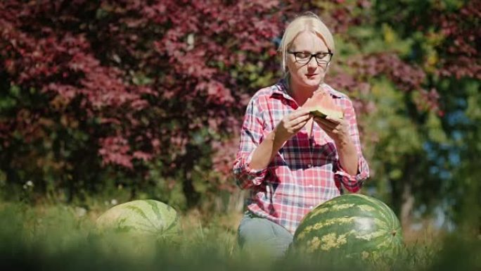 一个女人正在吃美味的西瓜。农民，丰收的概念