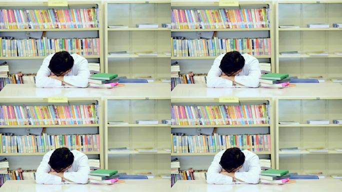 在图书馆努力学习。年轻的中国男孩在图书馆努力学习。入睡。