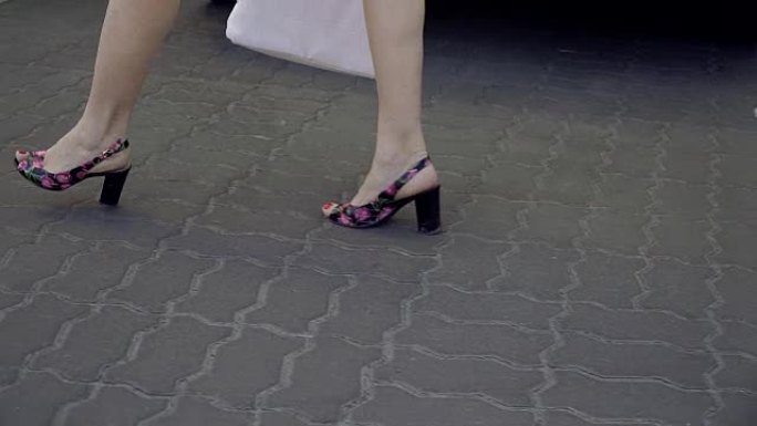 女性脚。女人的脚踩在脚后跟的沥青上