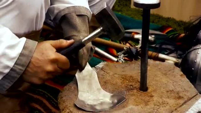 男人用锤子和铁砧铜匠手镯进行历史重建