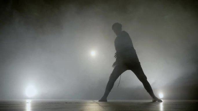 小男孩在舞台上表演现代艺术街舞，背景是烟雾