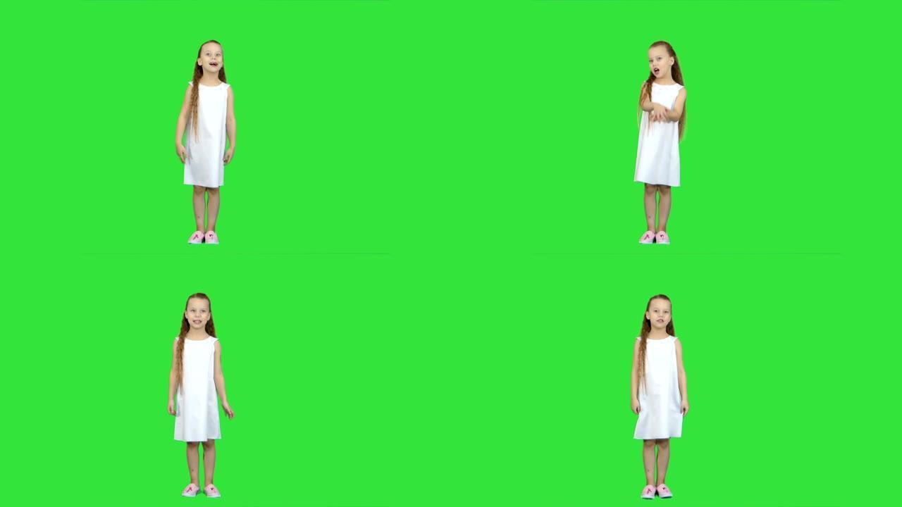 年轻的女士穿着可爱的连衣裙和白鞋，在绿色屏幕上唱着一首歌，色键