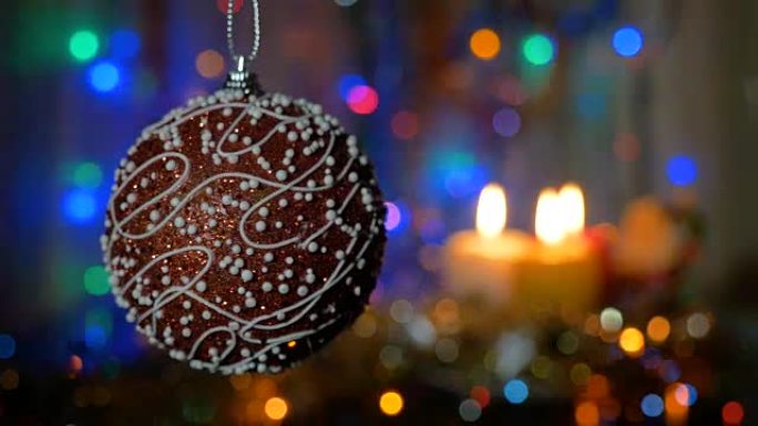 一个美丽的红球。新年和圣诞装饰品。燃烧蜡烛。闪光花环。背景模糊。