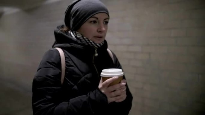 漂亮女人走过隧道，喝咖啡，冬天