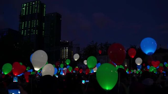 爱情盛宴的概念。夜城天空中的彩色氦气发光气球气球