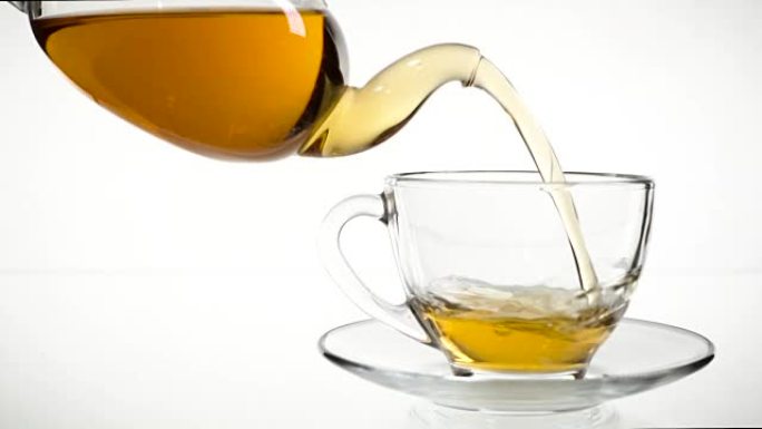 倒茶。将茶倒入玻璃透明茶杯中。喝茶时间。透明玻璃茶壶和茶杯。慢动作