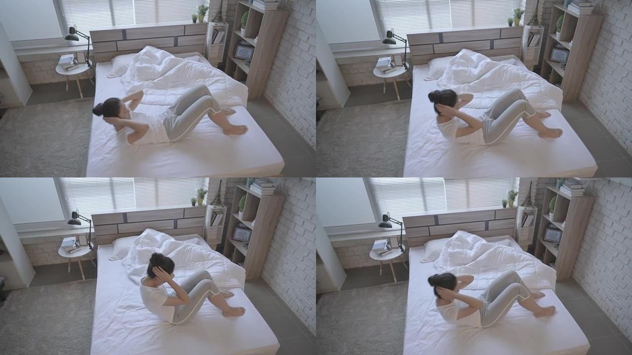 亚洲女性早上在床上锻炼，她感到精神焕发。