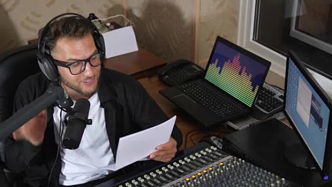 工作时，漂亮的广播节目主持人对着眼镜和耳机在广播演播室的麦克风上直播新闻