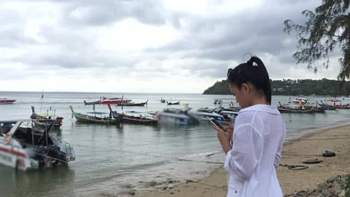 年轻女子用智能手机拍照出海