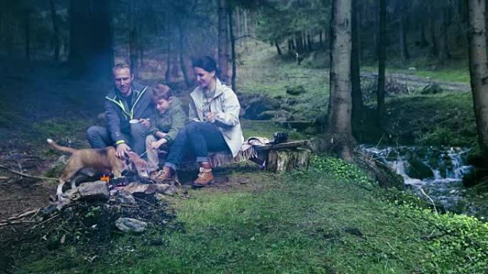 一家人坐在篝火前在森林里野餐