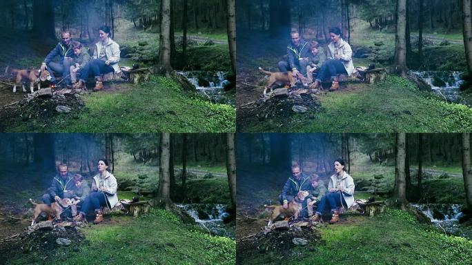 一家人坐在篝火前在森林里野餐