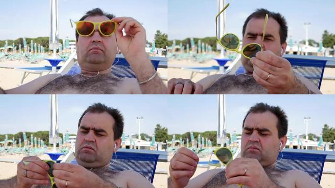 暑假、科技和人的概念 -- 戴着太阳镜的快乐年轻人，戴着智能手机和耳机听音乐，在沙滩巾上晒日光浴