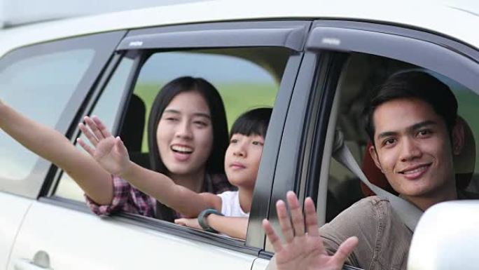 快乐的小女孩和坐在车里享受公路旅行和暑假的亚洲家庭玩尤克里里琴