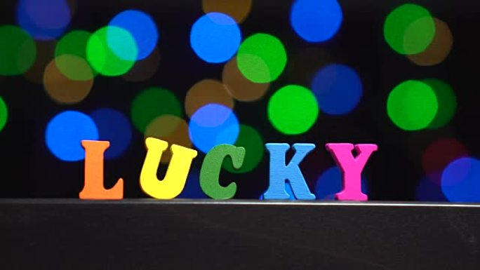 彩色单词 “幸运” 来自抽象模糊灯光前的多色木制字母bokeh背景