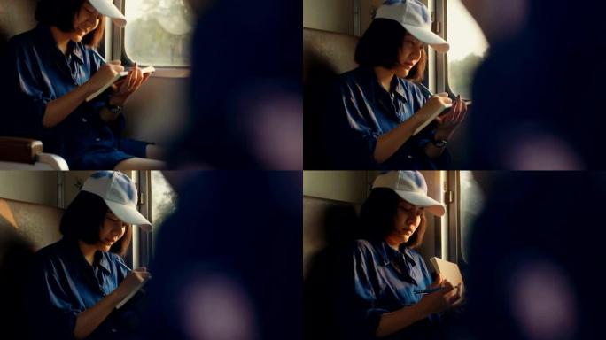 亚洲女子在乘火车旅行时正在写日记记录