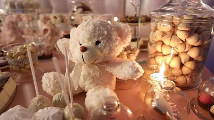 餐厅里的糖果棒，儿童派对，生日，一只脖子上有蝴蝶的白色泰迪熊，点燃蜡烛，桌上的泰迪熊