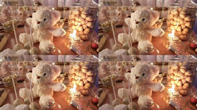 餐厅里的糖果棒，儿童派对，生日，一只脖子上有蝴蝶的白色泰迪熊，点燃蜡烛，桌上的泰迪熊
