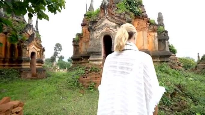 年轻女子在缅甸古老的佛教寺庙周围漫步。