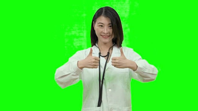 亚洲女医生在绿屏上显示双拇指