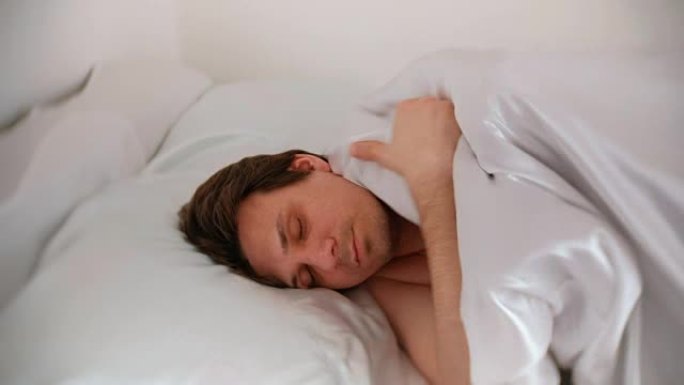 一个人睡在床上，盖着毯子。侧视图。