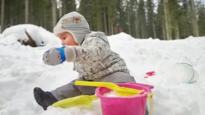 SLO MO的小孩坐在外面的雪地里，旁边是他的兄弟，玩得很开心