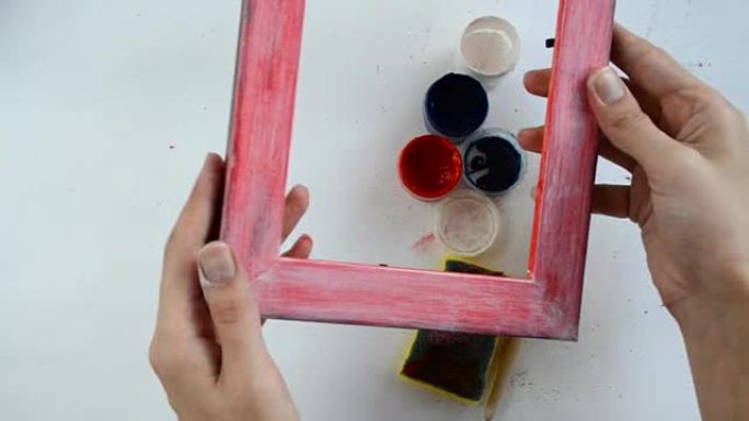 女孩拿起一个彩绘的木制相框，检查工作