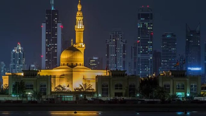 现代迪拜城市天际线与拉希德·哈迪斯清真寺在夜间时光倒流，水面上有照明的摩天大楼