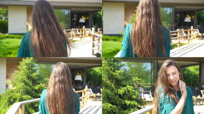 年轻女子戴着耳机听音乐。迷人的女性带着可爱的微笑，在咖啡馆里看着相机休息