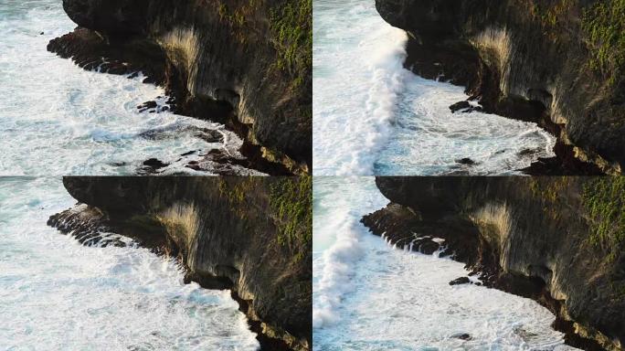 波浪撞击热带海滩上的岩石，形成飞溅的形状。岩石海滩上强大的波浪。印度尼西亚巴厘岛著名的乌鲁瓦图神庙。