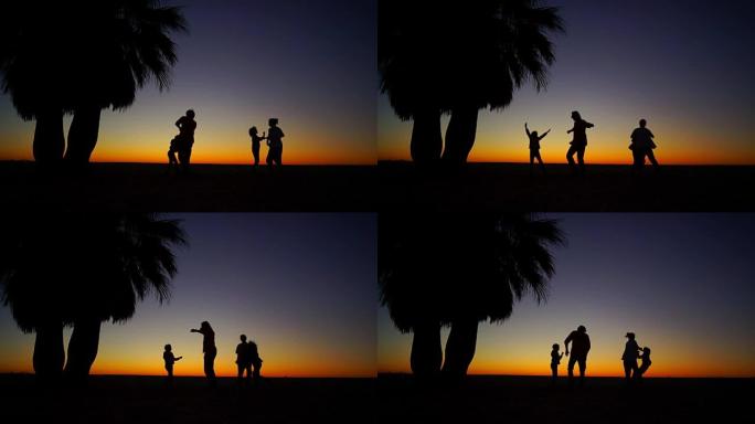 一家四口在棕榈树下的海滩上跳舞。美丽的热带日落。slown运动