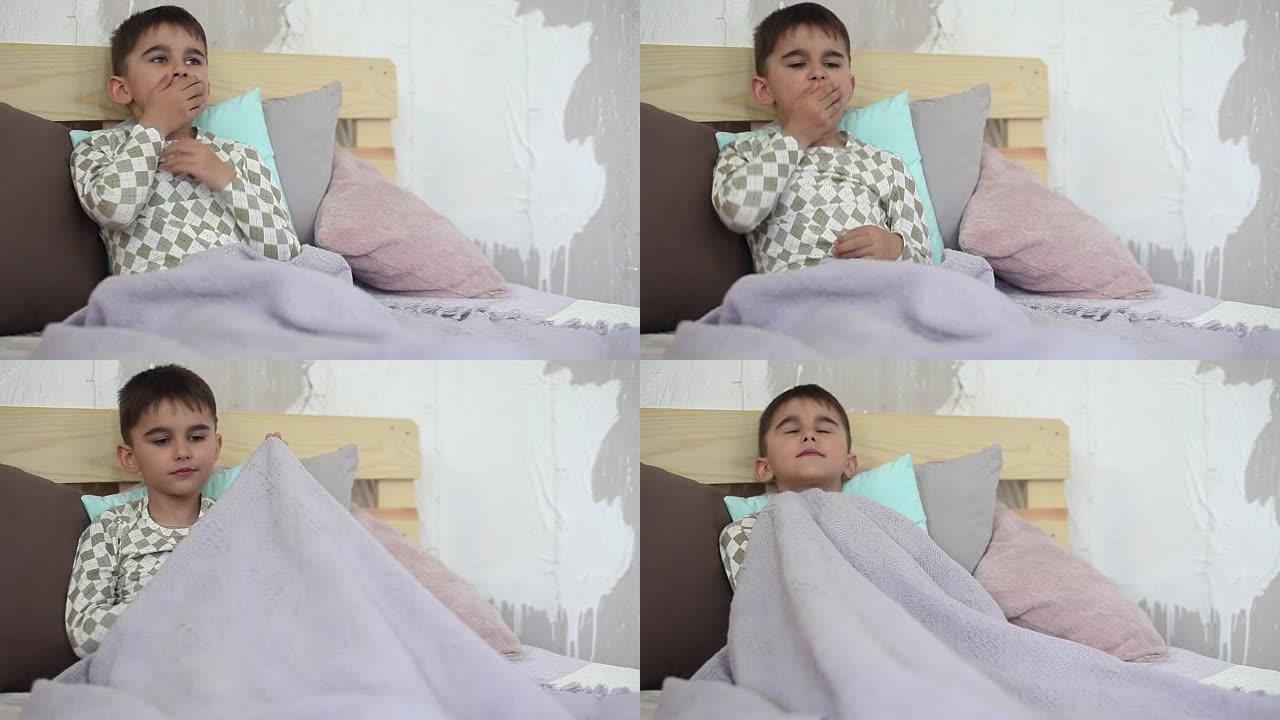 生病的小男孩坐在床上咳嗽，用毯子盖住自己