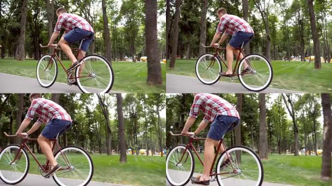 运动男在公园路骑自行车。年轻英俊的男人在户外骑老式自行车。健康积极的生活方式。侧视图特写慢动作低角度