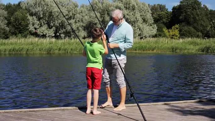 河泊位上有钓鱼竿的快乐爷爷和孙子