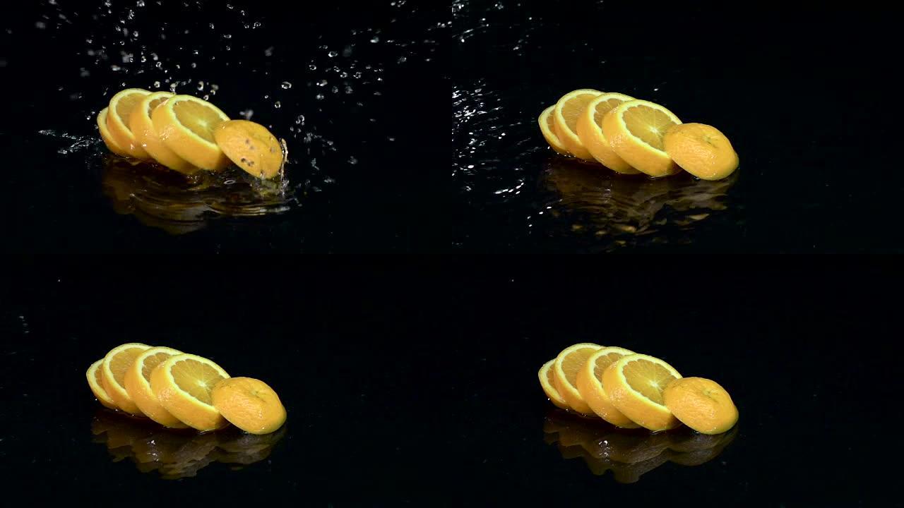 橘子落入水中时会溶解成薄片。黑色背景。慢动作