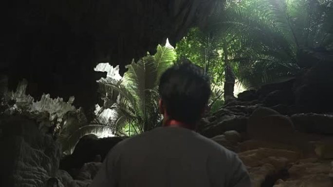 年轻旅行者的背部在泰国Uthaithani的古代森林的洞穴中