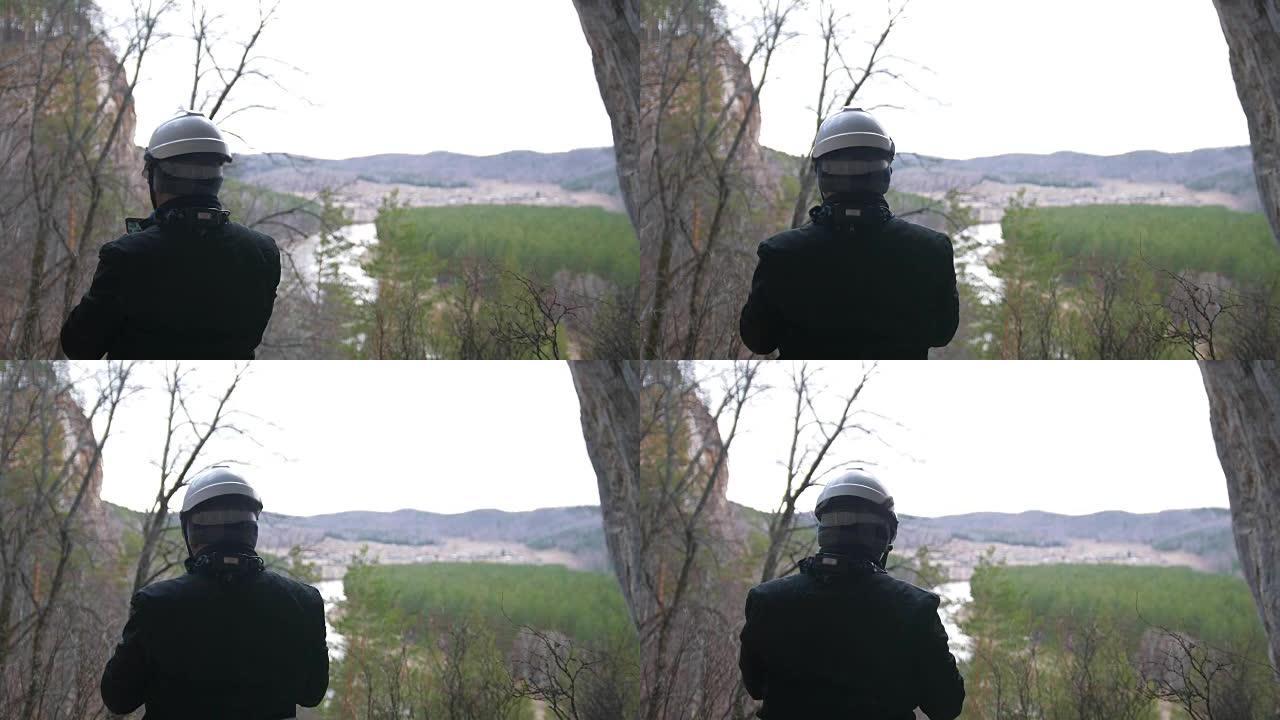 戴着头盔的男性徒步旅行者带着智能手机站在山顶