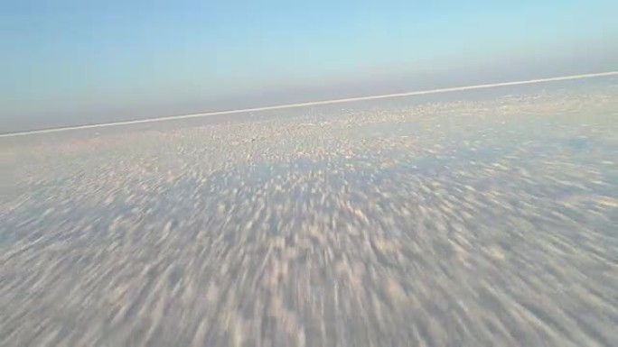 低角度快速飞越白色盐湖，并带有盐沉积物。第一视点模式。鸟瞰图。