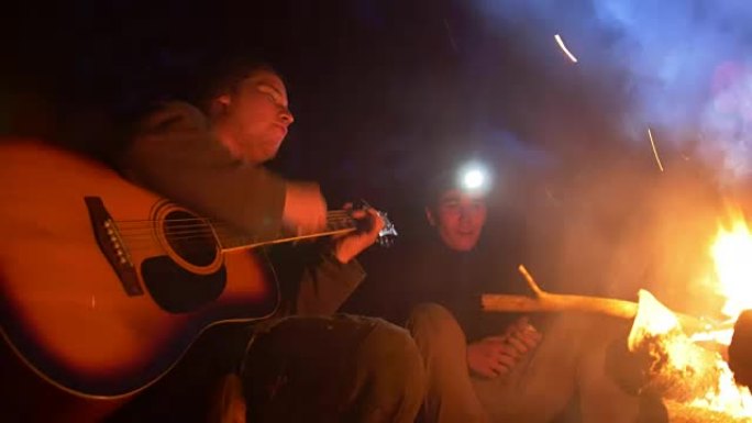 夜木篝火旁年轻朋友唱歌弹吉他
