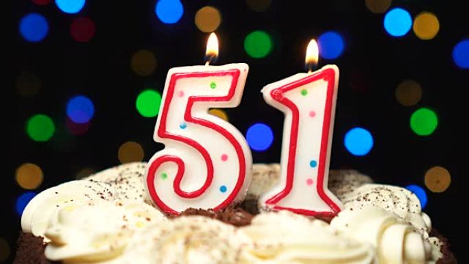 蛋糕上的第51号-五十一岁生日蜡烛燃烧-最后吹灭。彩色模糊背景