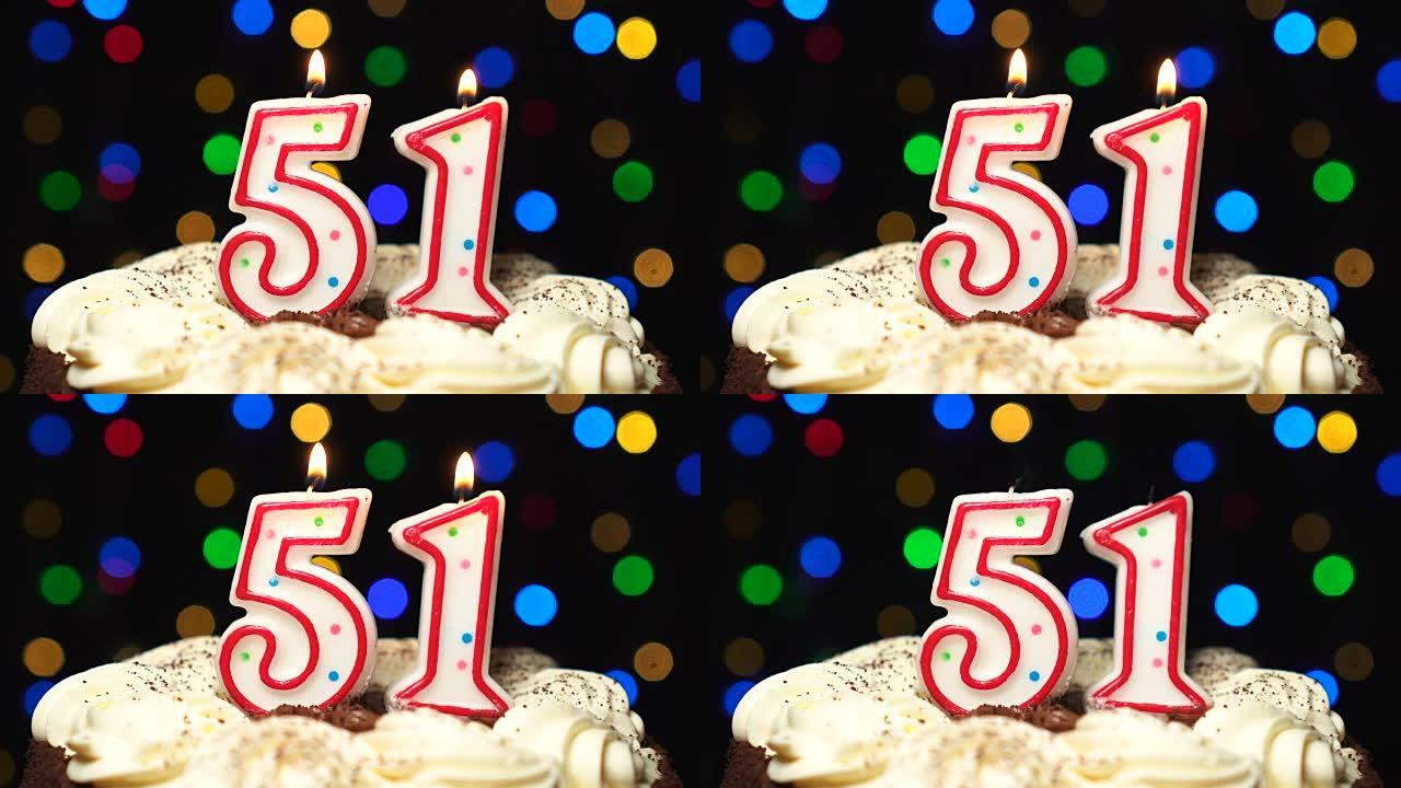 蛋糕上的第51号-五十一岁生日蜡烛燃烧-最后吹灭。彩色模糊背景