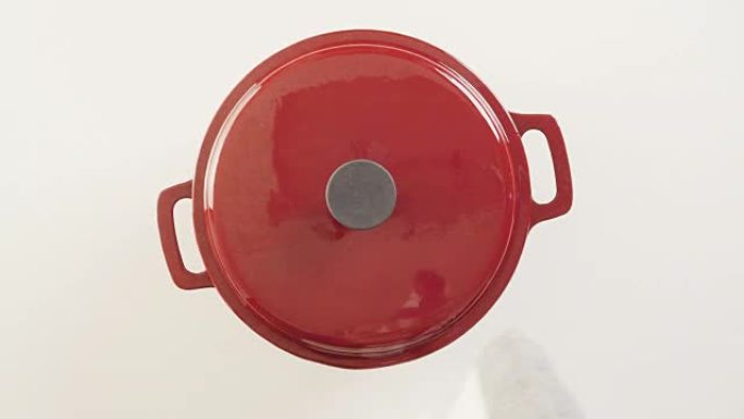白色背景的红色搪瓷铸铁覆盖荷兰烤箱。