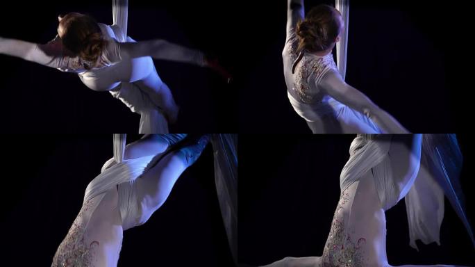 白色丝绸的女空中体操运动员完成了她的表演。慢动作