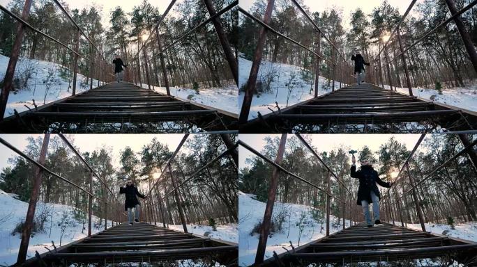 新手博客作者使用智能手机和设备拍摄自己的视频。穿着时髦的男人爬下森林的台阶