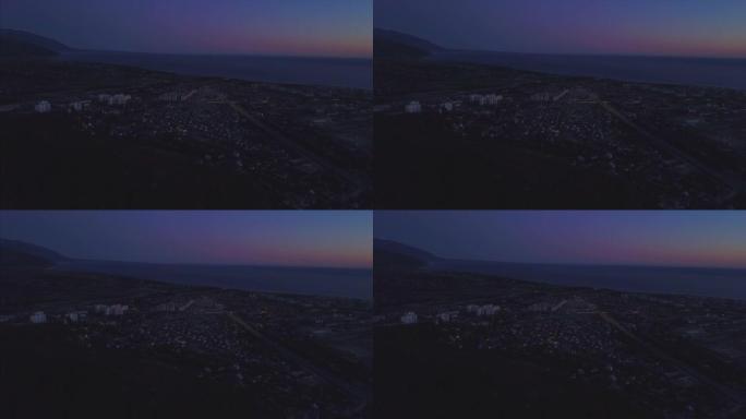 鸟瞰索契市的夜景。夹。从空中俯瞰索契全景。房屋，街道，树木，夜空可见。在远处你可以看到大海。俄罗斯索