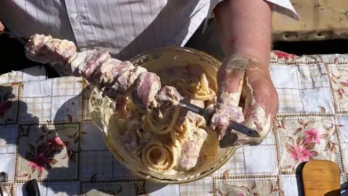胖子把腌制的生肉放在串肉上，在大自然上烤肉串