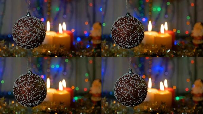 一个大红色的球。新年和圣诞装饰品。燃烧蜡烛。闪光花环。背景模糊。