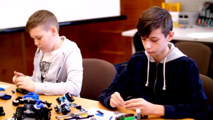 12岁的男孩，从立方体，盘子，电路，电线中扮演设计师。小发明家从设计师的不同部分创造机器人、机器