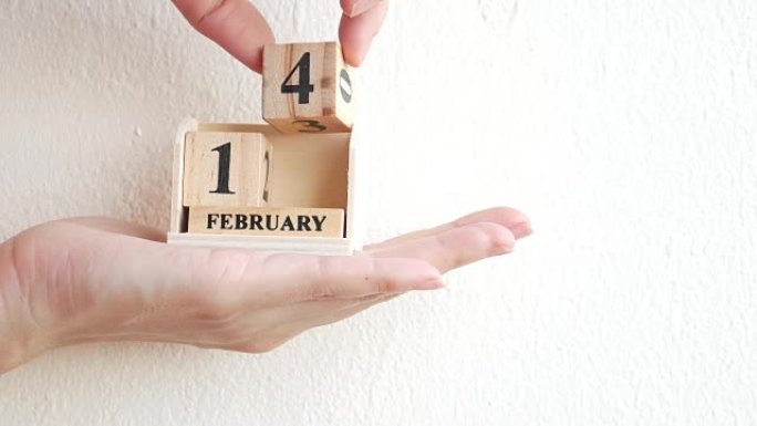 手上2月14日的木制日历展示