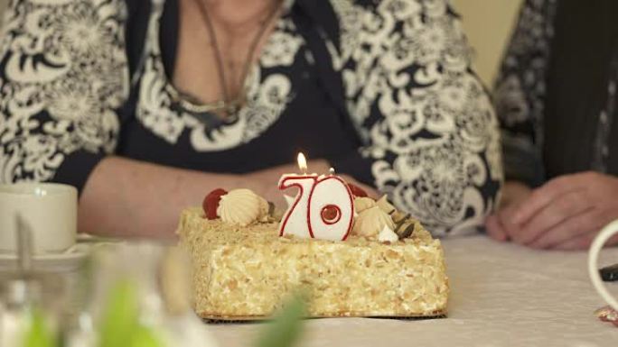 70周年庆典上的老年人。70号燃烧蜡烛的蛋糕。